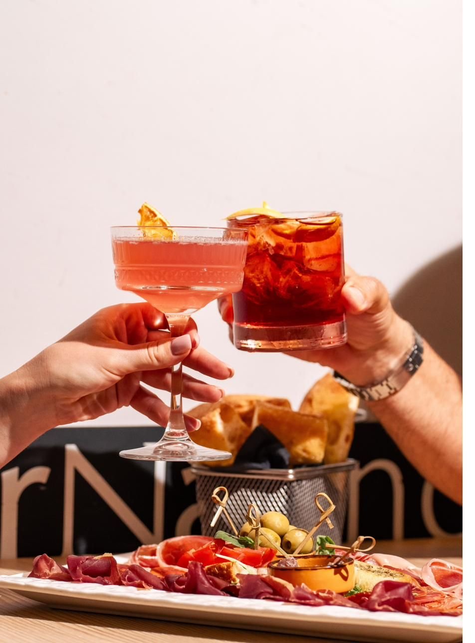 Brindisi con due cocktail su un tagliere di salumi