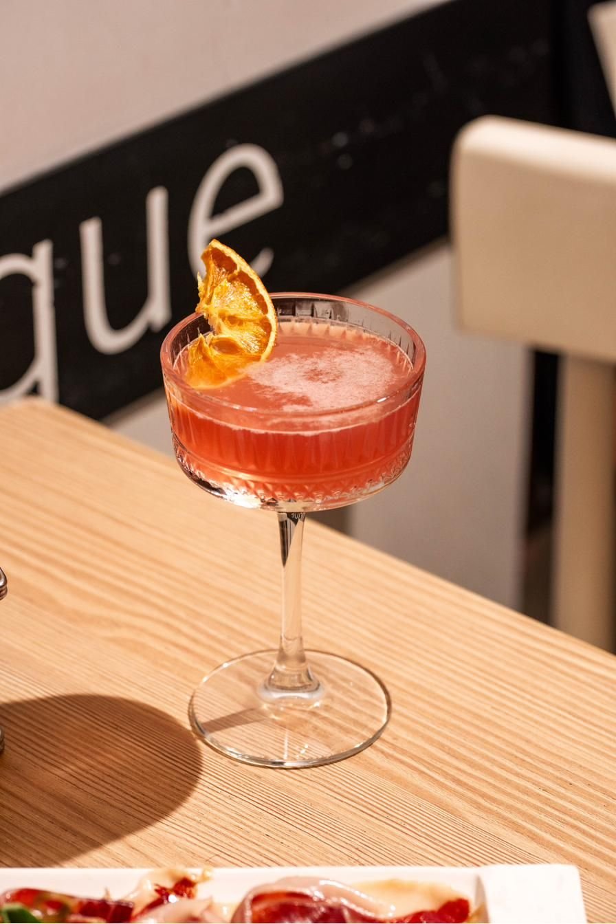 Cocktail rosa con scorza d’arancia su un tavolo di legno