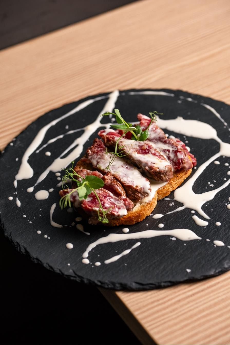 Tagliata di carne su crostone con salsa bianca su ardesia