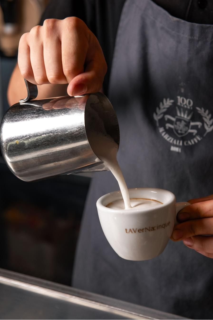 Latte versato in una tazza di cappuccino al bancone