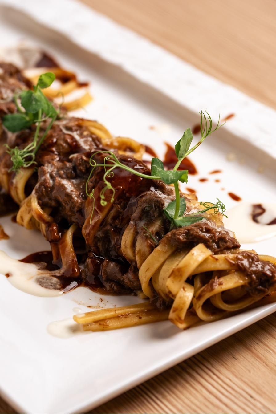 Tagliatelle con ragù e pecorino su piatto rettangolare